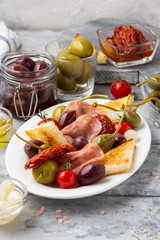 Italian antipasti, olives, capers, sun-dried tomatoes , olive oil, bread (ciabatta, baguette, croutons). Mediterranean assortment of delicious food, wine snacks