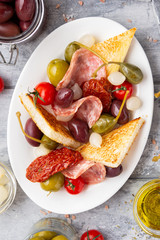 Italian antipasti, olives, capers, sun-dried tomatoes , olive oil, bread (ciabatta, baguette, croutons). Mediterranean assortment of delicious food, wine snacks