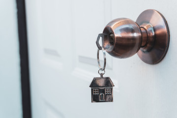 House key in the doorknob  of a white door