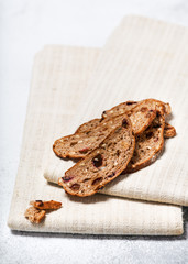 Sliced of rusk bread made from wheat,  nuts, plums and grapes on a linen kitchen towel. Homemade healthy food concept. Copy space.