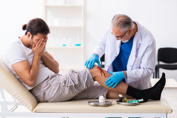 Leg injured man visiting old doctor in first aid concept