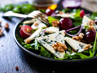 Fresh salad - blue cheese, grapes, spinach, walnuts on black stone board