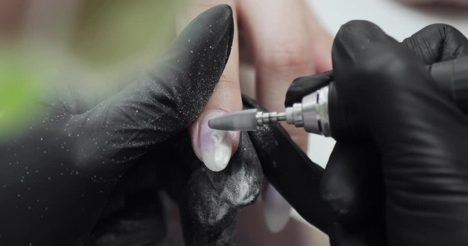 Manicure master removing old shellac from woman's nail using electric machine. Making manicure for woman using electric nail file drill machine, hands closeup view. Hardware manicure in beauty salon.