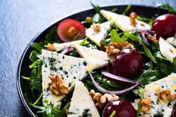 Fresh salad - blue cheese, grapes, spinach, walnuts on black stone board