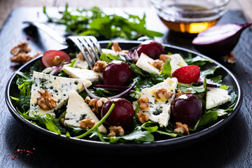 Fresh salad - blue cheese, grapes, spinach, walnuts on black stone board