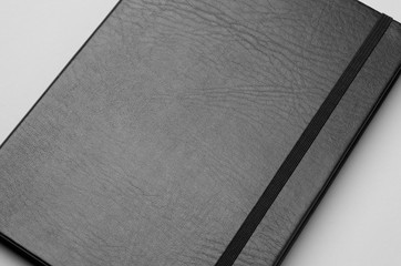 Black notebook mockup on a grey background. Closeup.