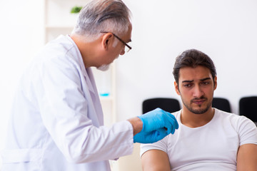 Obraz premium Leg injured man visiting old doctor in first aid concept