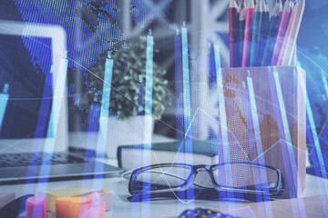 Financial chart hologram with glasses on the table background. Concept of business. Double exposure.