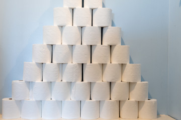 A huge pile of toilet paper stacked up next to a toilet