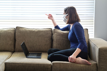 Young adult woman diagnosed as infected in Coronavirus in a self home isolation lock down quarantine looking outside a window