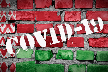 Flag of Belarus on the brick wall with sprayed stencil COVID-19 on it. 2019 - 2020 Novel...