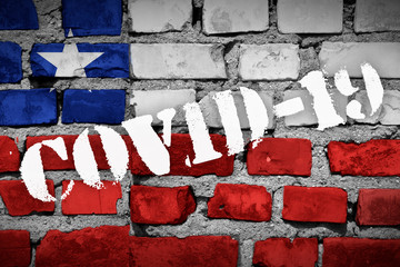 Flag of Chile on the brick wall with sprayed stencil COVID-19 on it. 2019 - 2020 Novel Coronavirus...