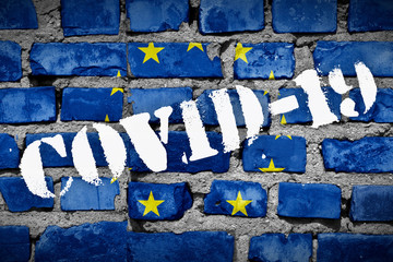 Flag of European Union on the brick wall with sprayed stencil COVID-19 on it. 2019 - 2020 Novel...