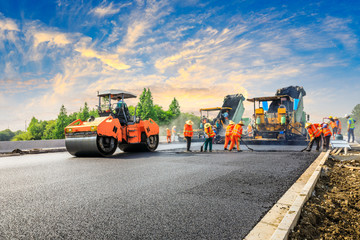 Construction site is laying new asphalt road pavement,road construction workers and road construction machinery scene.highway construction site landscape. - Powered by Adobe