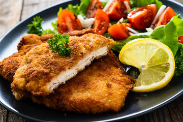 Pork chops with lemon and vegetable salad on wooden background