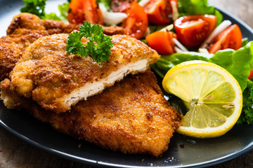 Pork chops with lemon and vegetable salad on wooden background