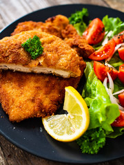 Pork chops with lemon and vegetable salad on wooden background