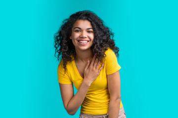 Portrait of beautiful smiling dark skinned girl wearing bright colored yellow t-shirt isolated over...