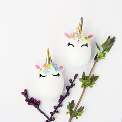 Easter concept. Unicorns shaped eggs. And twigs with buds and blooming leaves