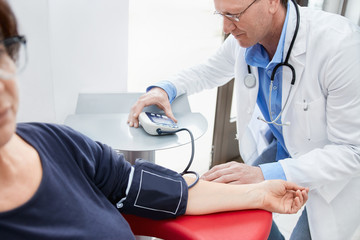 Doctor using digital blood pressure monitor on patient