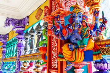 Representation of Hindu gods and tourists climbing a colorful stairs leading to the Batu Caves in...