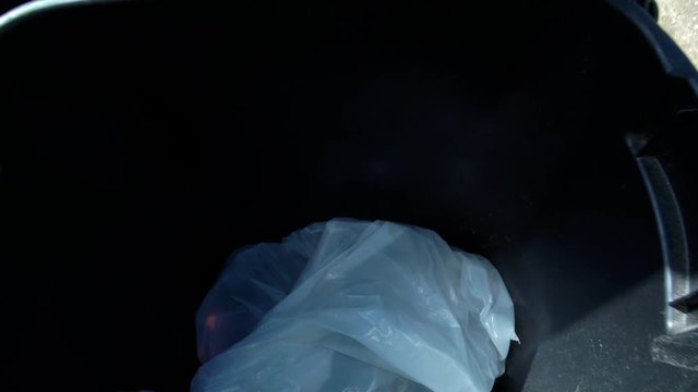 Camera slowly descends into an open trash can.