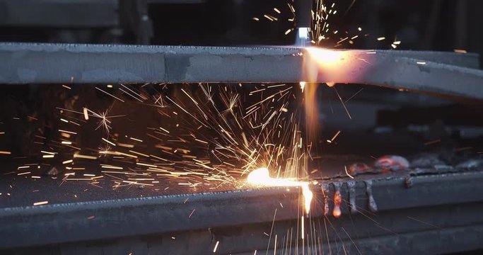 Plasma cutter cuts metal in an industrial company - High energy through heat and electrical power - Special tools in the metal industry - Sparks and fire in high resolution 4K shot - Close up