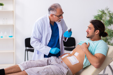 Injured young man visiting experienced male doctor