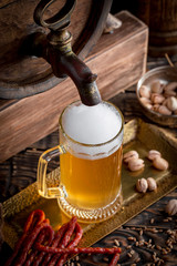 Light frothing beer in a glass, on an old background.