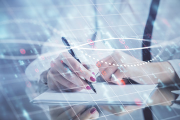 Double exposure of hands making notes with forex chart huds. Stock market concept.