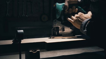 Close-up, joiner prepare jig saw settings for work with thick elm plank, lowlight 