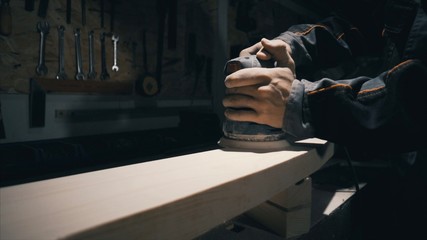 Close-up, worker grinds the wood of angular grinding machine