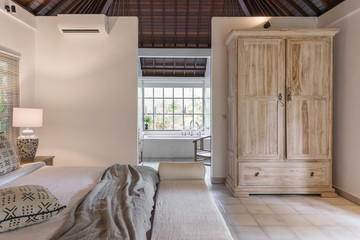 White interior in cozy bedroom with bed, windows and cupboard