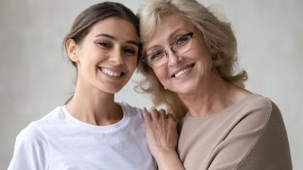 Portrait of happy senior mother and grown-up daughter hugging showing love and care, smiling mature...