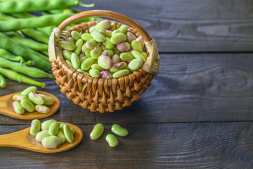 raw peeled beans in a wicker basket and bean pods on a wooden background. fresh green beans close -up.