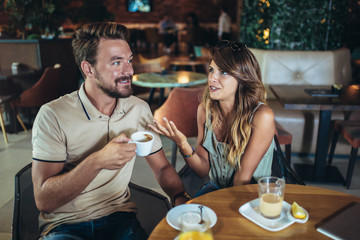 Young couple arguing while sitting and drinking coffee in restaurant