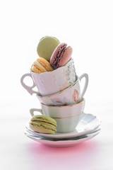 Colorful macaroons cake, macaroons of different flavors and colors in stacked cups on white table background, food background
