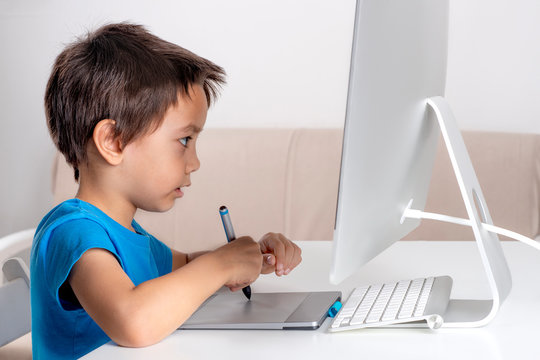 Little boy browses the internrt on a  desktop computer. Modern lifestyle.