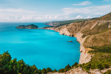 Kefalonia west coastline. Assos village town and Frourio peninsular. Beautiful blue bay with brown limestone rocks and white clouds on horizon. Greece