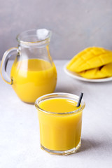 Glass of Tasty Ripe Mango Juice and Ripe Sliced Mango on Light Gray Background Vitamin and Healthy Drink Vertical