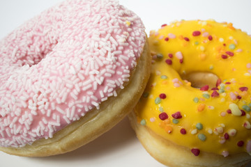 Closeup of delicious sweet glazed donuts with flakes on a white background.