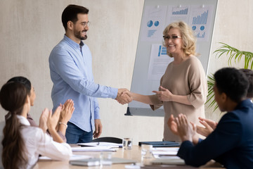 Smiling businesswoman shake hand of male employee greeting with work achievement at briefing, happy...