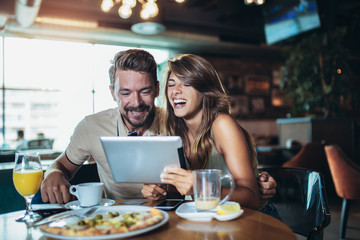 Young couple in a restaurant looking at digital tablet.
