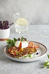 Zucchini fritters with poached egg and fried bacon. Low carb keto breakfast.