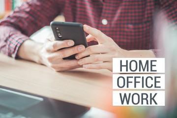 Home office concept: Man is typing on his black mobile phone, Text 