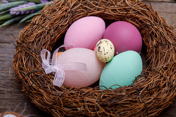 Easter eggs in nest on rustic wooden background.
