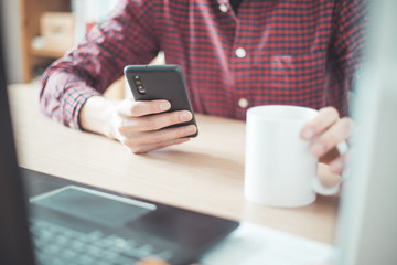 Home office concept: Man is typing on his black mobile phone