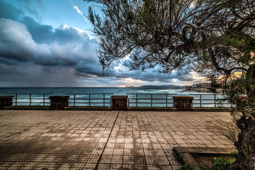 Alghero seafront under a cloudy sky at sunset