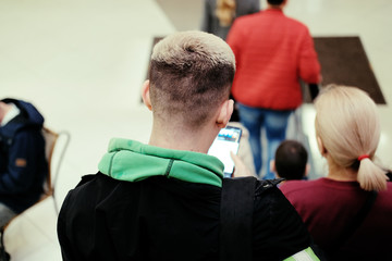 A young man with a smartphone in his hands goes down the escalator.