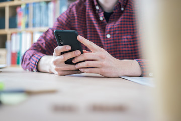 Home office concept: Man is typing on his black mobile phone